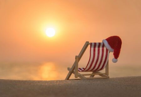 Ein Liegestuhl mit einer Samichlaus-Mütze am Strand bei Sonnenuntergang